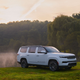 A photo of a white Grand Wagoneer SUV in a field.